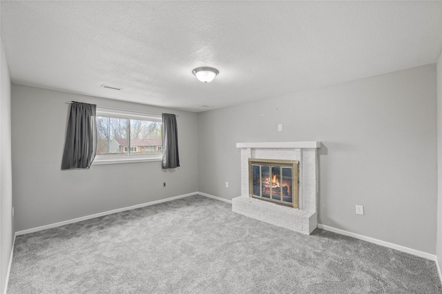 unfurnished living room with a textured ceiling, visible vents, a fireplace, baseboards, and carpet flooring