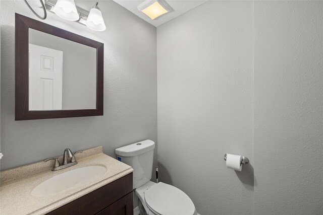 half bathroom with vanity and toilet