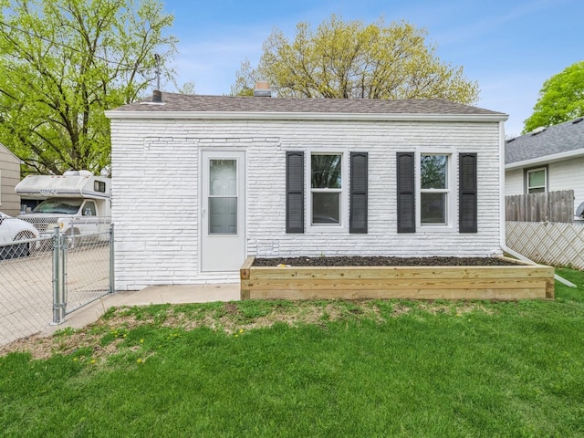back of property featuring a yard, fence, and a gate