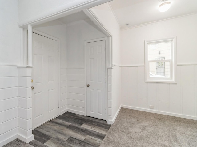 empty room with ornamental molding, wainscoting, and dark wood finished floors