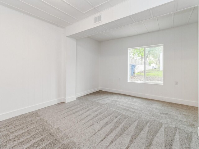 carpeted empty room featuring baseboards and visible vents