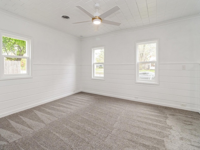 unfurnished room featuring visible vents, ornamental molding, ceiling fan, and a wainscoted wall