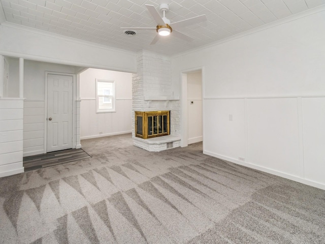 unfurnished living room with carpet flooring, ceiling fan, ornamental molding, and a fireplace