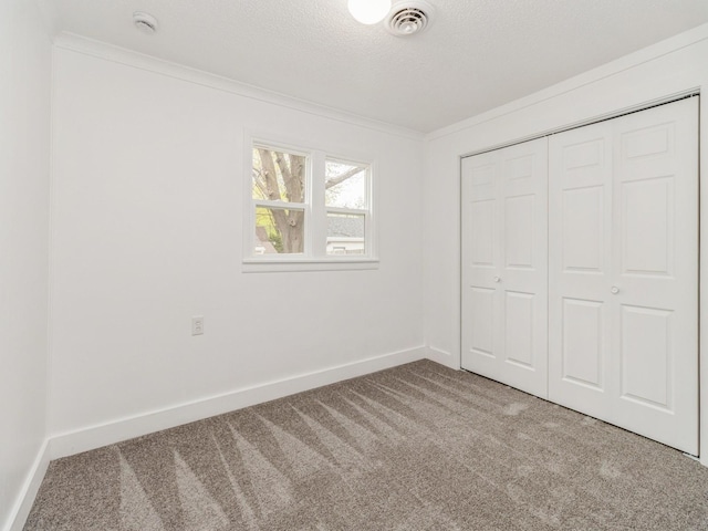 unfurnished bedroom featuring a closet, baseboards, ornamental molding, and carpet flooring
