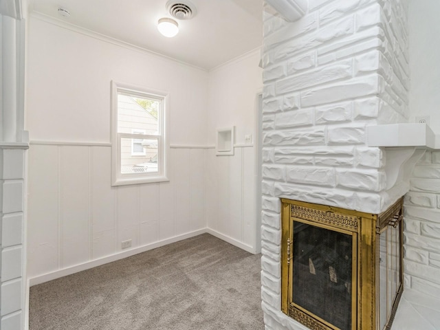 unfurnished living room featuring crown molding, a fireplace, carpet floors, a wainscoted wall, and visible vents
