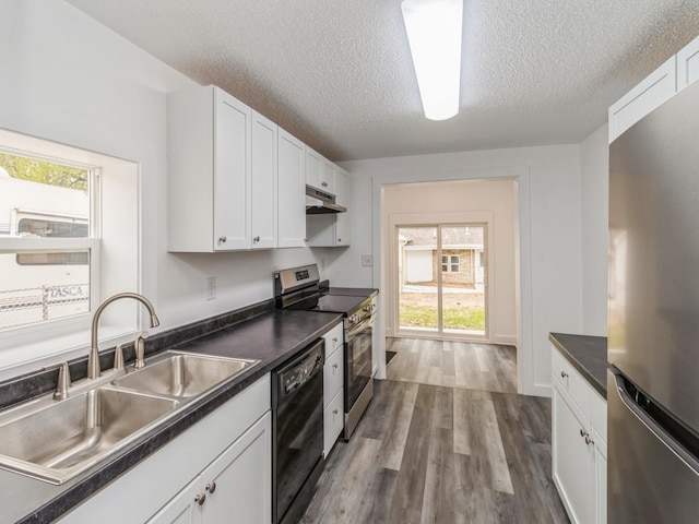 kitchen with a sink, appliances with stainless steel finishes, under cabinet range hood, and dark countertops