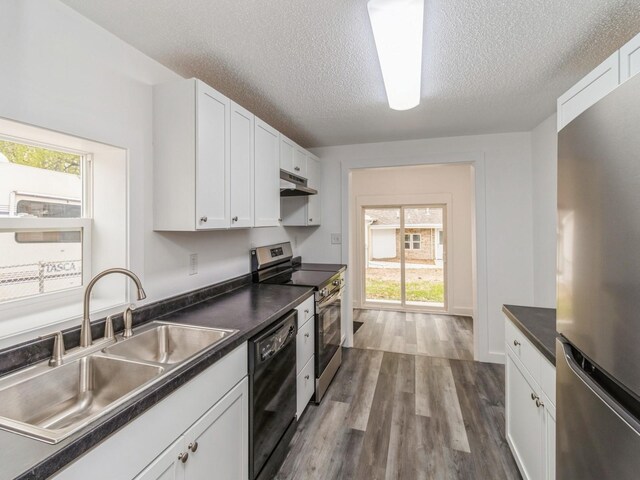 4040 6th Ave, Des Moines, IA 50313 - kitchen featuring stainless steel appliances, a sink, under cabinet range hood, dark countertops, and a textured ceiling
