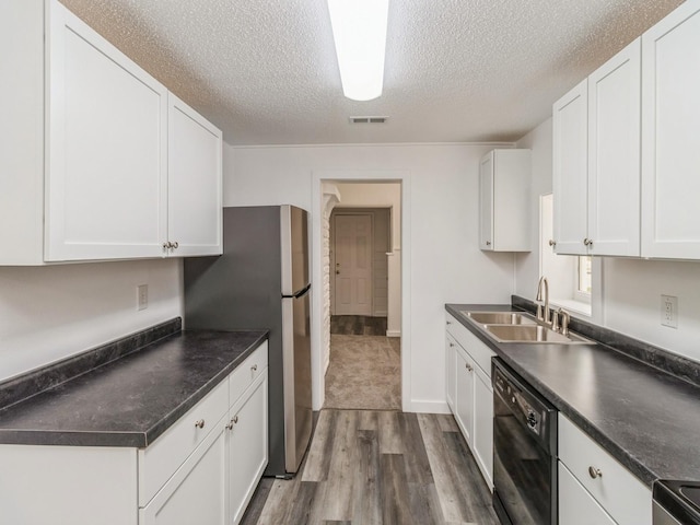 kitchen with dark countertops, a sink, a textured ceiling, black dishwasher, and dark wood-style floors