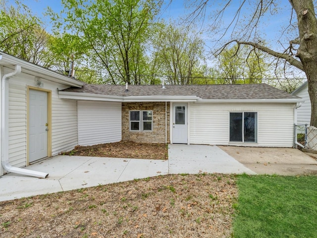 rear view of house with a patio, a shingled roof, and fence