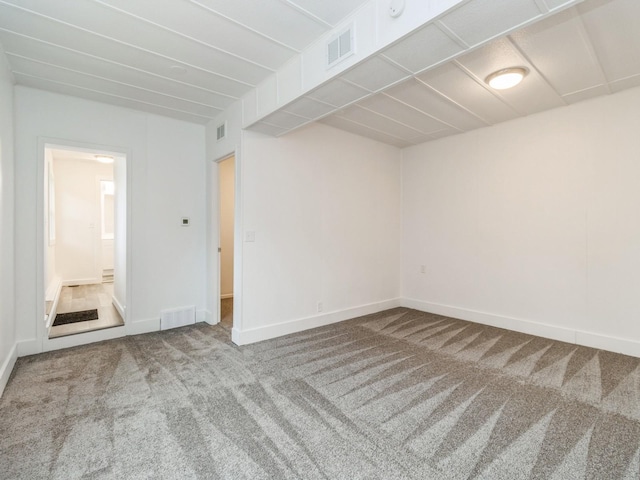 carpeted empty room featuring visible vents and baseboards
