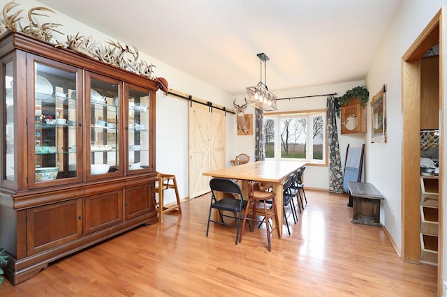 dining room with baseboards, a barn door, and light wood-type flooring