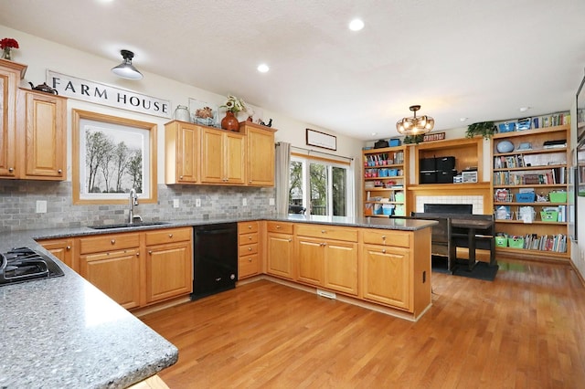 kitchen with a sink, light wood-style floors, a peninsula, a tile fireplace, and black appliances
