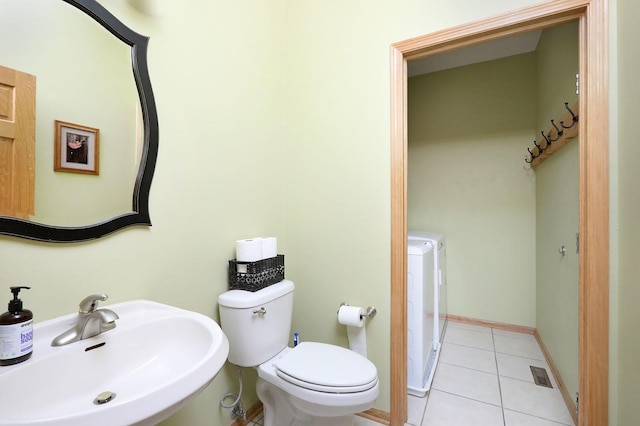 bathroom with visible vents, tile patterned flooring, a sink, toilet, and separate washer and dryer