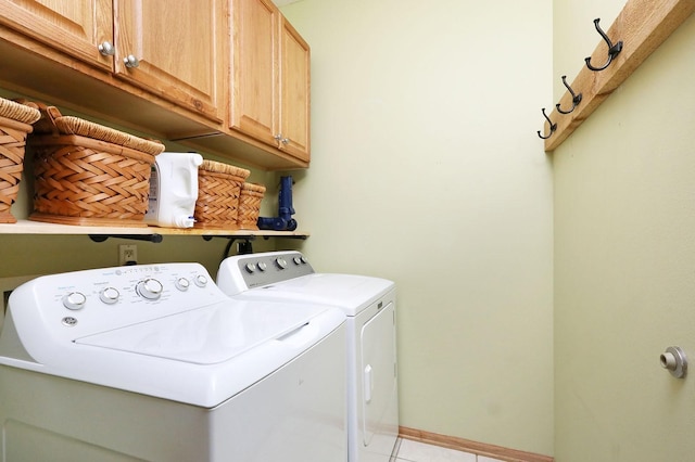 washroom featuring washer and dryer, baseboards, light tile patterned floors, and cabinet space