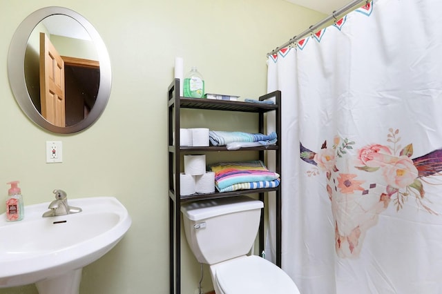 bathroom featuring toilet, a shower with curtain, and a sink