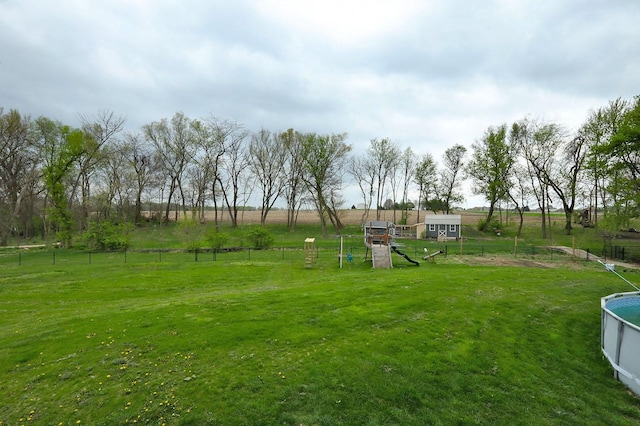 view of yard featuring fence, a playground, and a rural view