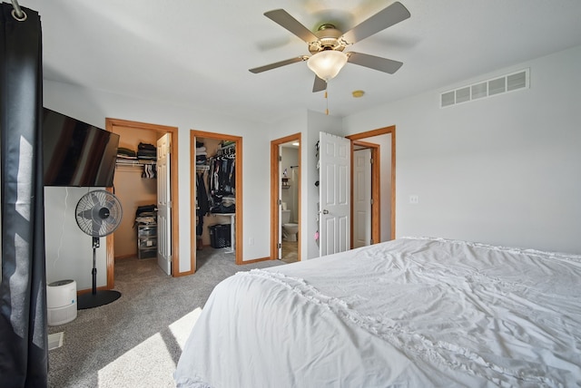 carpeted bedroom with visible vents, a ceiling fan, and a walk in closet