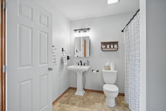 bathroom with toilet, baseboards, curtained shower, and a textured ceiling