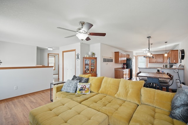 living area featuring baseboards, light wood finished floors, and ceiling fan