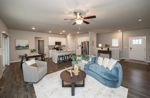 living area with dark wood-type flooring, a ceiling fan, baseboards, and recessed lighting