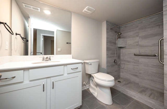 bathroom featuring toilet, visible vents, tiled shower, and vanity