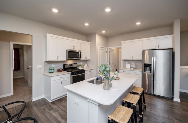 kitchen with a center island with sink, backsplash, a kitchen bar, and stainless steel appliances