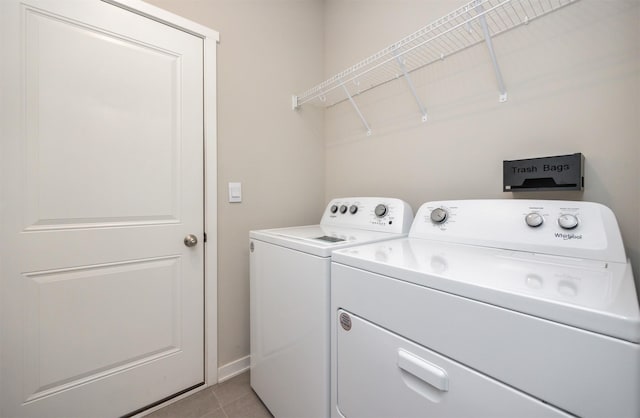 washroom featuring baseboards, light tile patterned floors, laundry area, and washer and clothes dryer