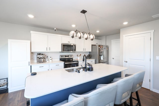 kitchen featuring a sink, a breakfast bar area, white cabinets, and stainless steel appliances