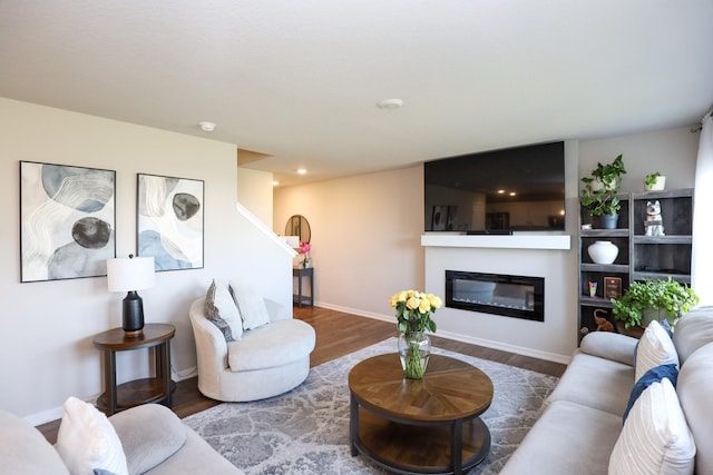 living room with baseboards, a glass covered fireplace, and wood finished floors