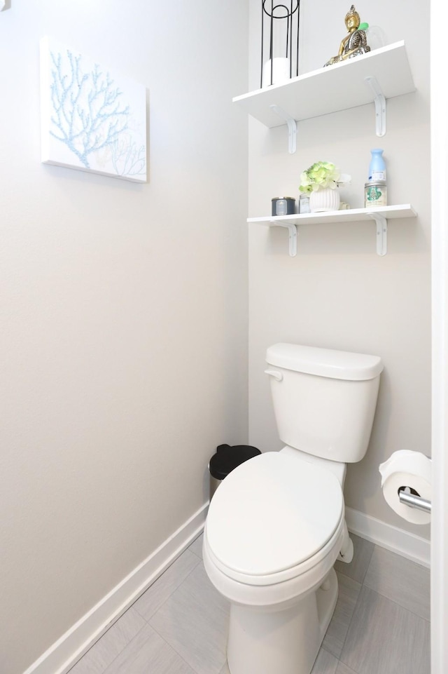 bathroom with baseboards, tile patterned flooring, and toilet