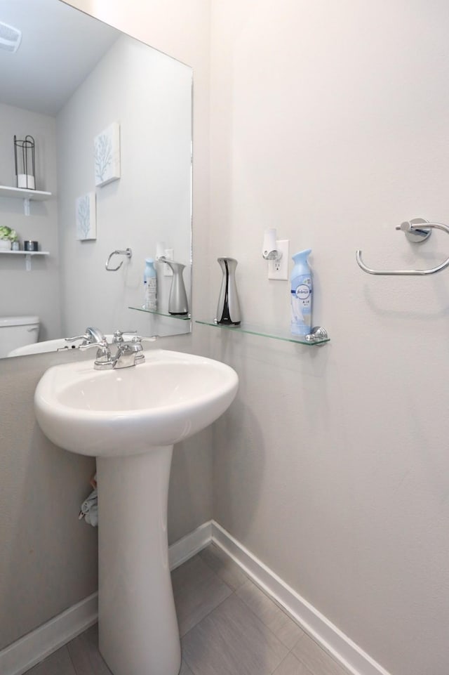 half bath with toilet, baseboards, and visible vents