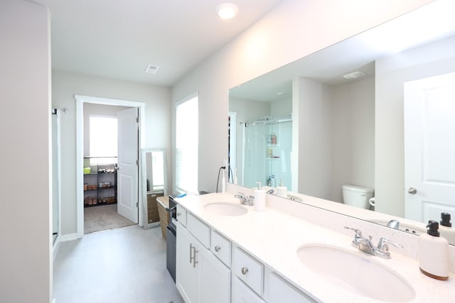 full bathroom with a sink, a shower stall, toilet, and double vanity