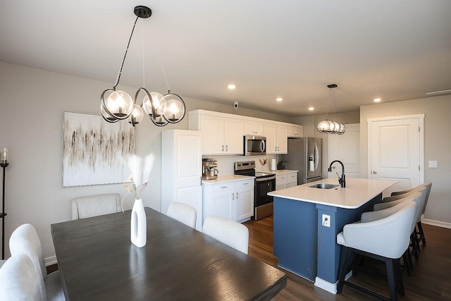 270 NW Charlestown Ln, Waukee, IA 50263 - kitchen featuring stainless steel appliances, a chandelier, an island with sink, dark wood-style flooring, and white cabinetry