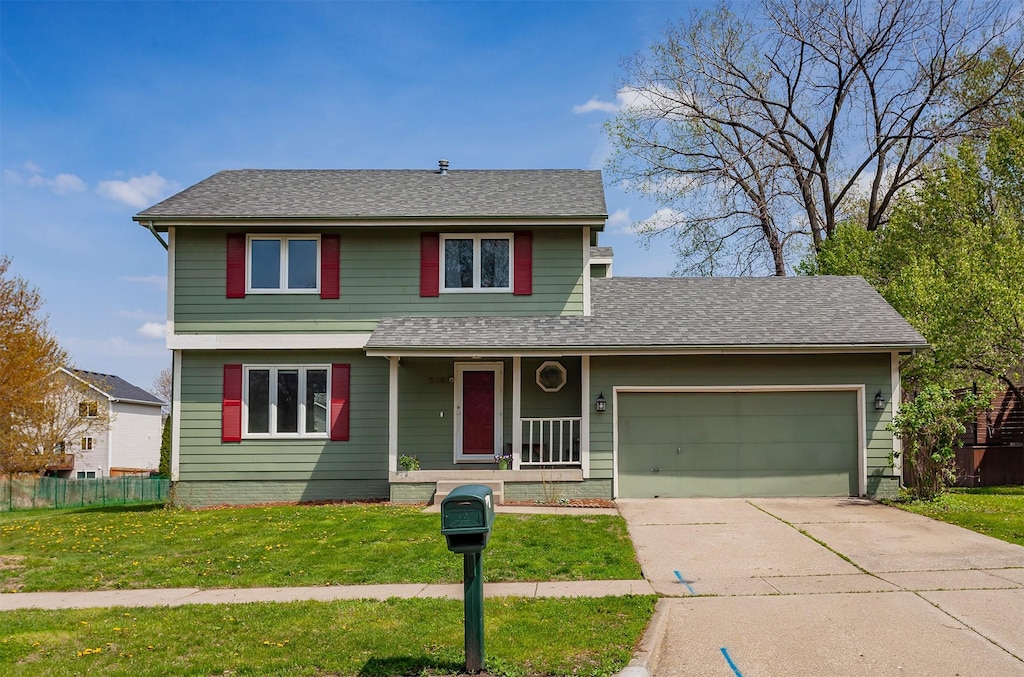 traditional-style house with fence, an attached garage, a porch, a front yard, and driveway