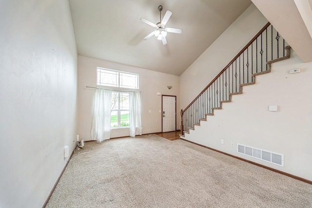 unfurnished living room with carpet floors, high vaulted ceiling, stairs, a ceiling fan, and visible vents