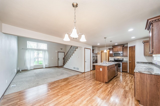 kitchen featuring visible vents, a sink, a chandelier, stainless steel appliances, and light wood-style flooring