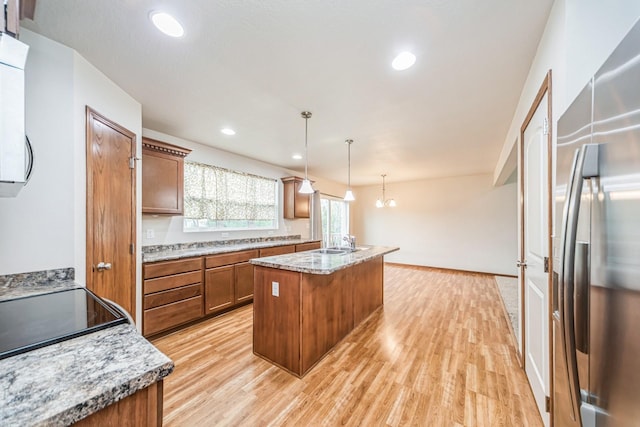 kitchen featuring stainless steel fridge, light wood-style flooring, brown cabinets, and a kitchen island