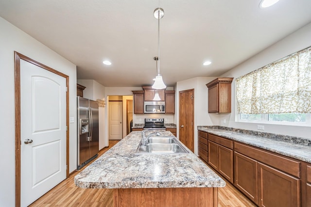 kitchen featuring a sink, light wood-style flooring, decorative light fixtures, and stainless steel appliances
