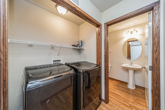 clothes washing area featuring baseboards, laundry area, light wood-type flooring, and washer and dryer