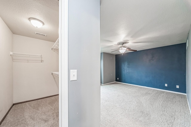 interior space featuring visible vents, a ceiling fan, a textured ceiling, and baseboards