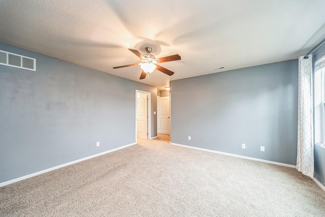 carpeted empty room featuring baseboards, ceiling fan, and visible vents
