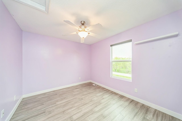 empty room featuring baseboards, a ceiling fan, light wood-style flooring, and visible vents
