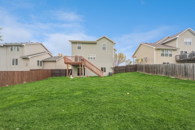back of property with a lawn, a deck, stairs, and a fenced backyard