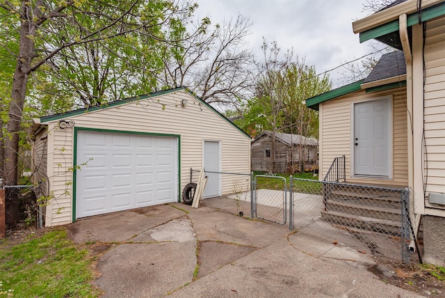 detached garage with fence, driveway, and a gate