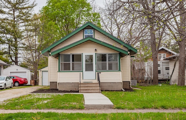 view of front of house with a detached garage, a front yard, an outbuilding, and entry steps