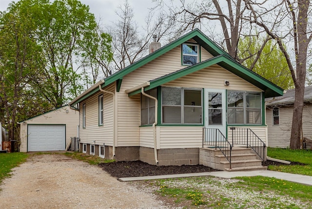 bungalow-style house featuring driveway, a chimney, an outbuilding, a sunroom, and a detached garage