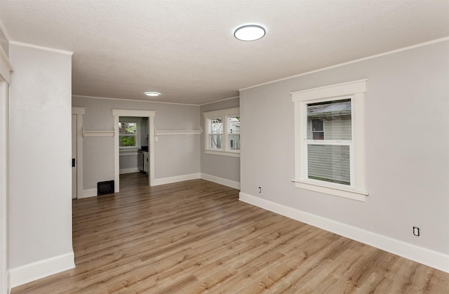 spare room with baseboards, ornamental molding, and light wood-style flooring