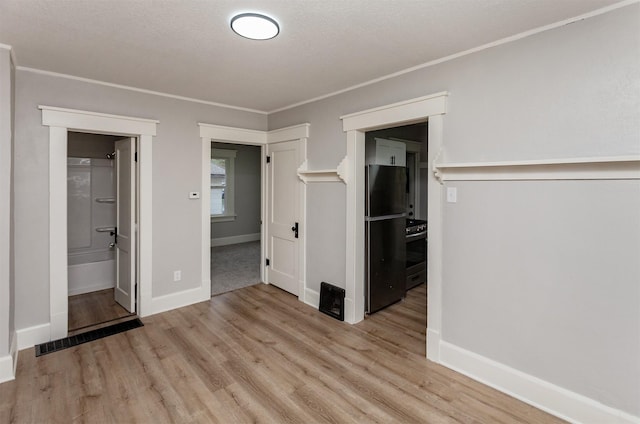 unfurnished bedroom with baseboards, freestanding refrigerator, wood finished floors, and ornamental molding