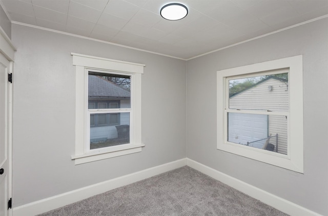 carpeted spare room featuring crown molding and baseboards