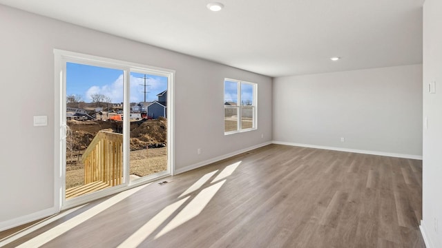 unfurnished room with baseboards, recessed lighting, wood finished floors, and visible vents